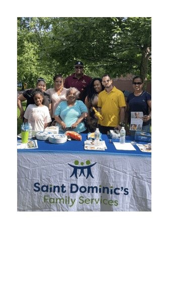 Group photo of EFFC Team posing behind a table that shows Saint Dominic's Familiy Services and flyers they provided to let the community know how to become a foster parent