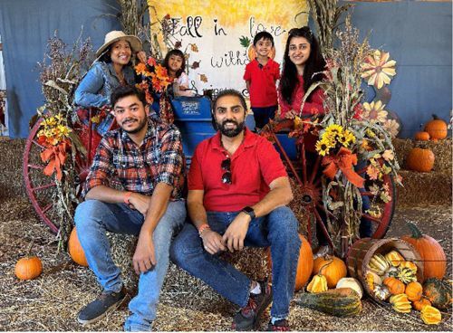 Two Men, possibly brothers, and their families pose for a photograph among hay bales and wagon wheels