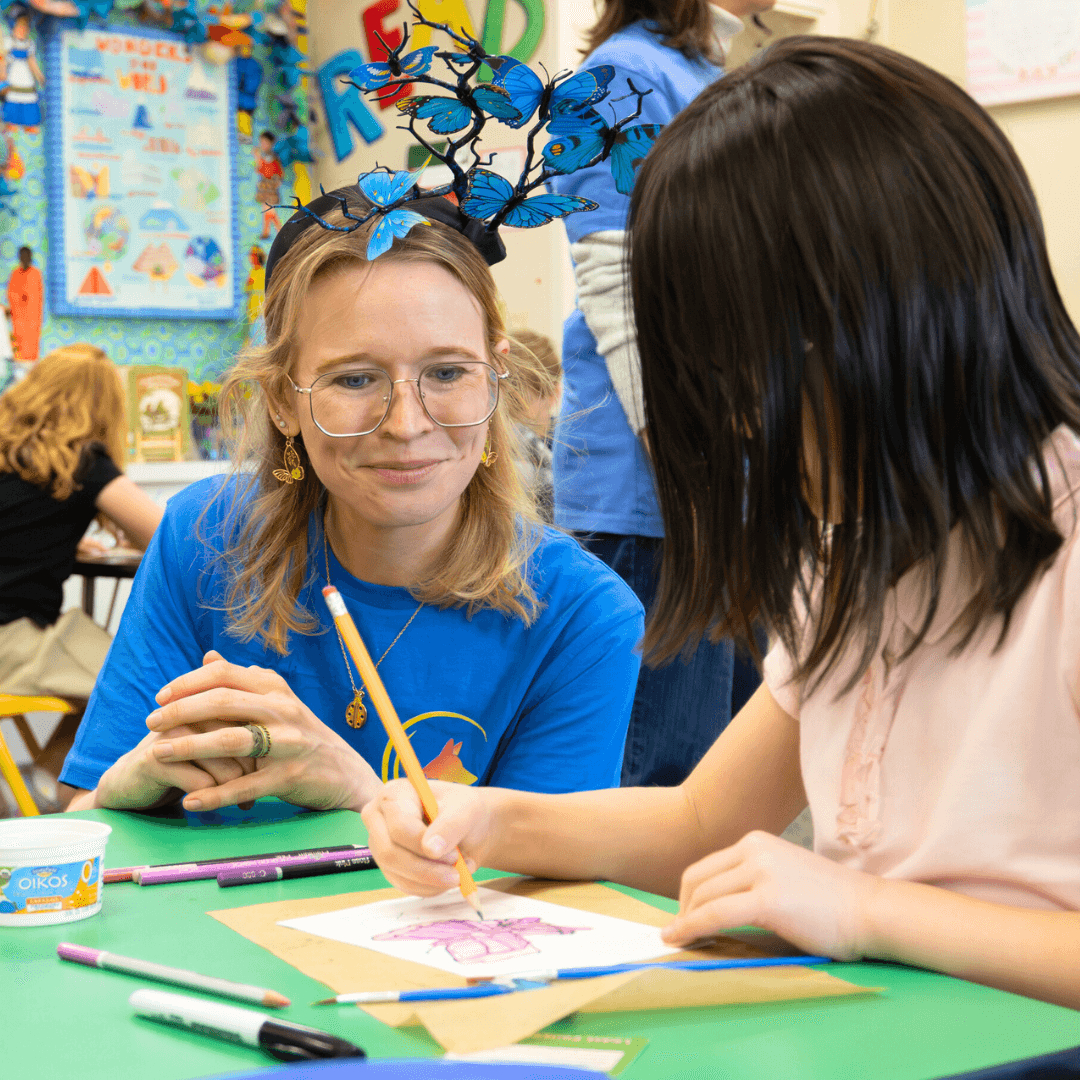 Facilitator helping a student color a butterfly drawing