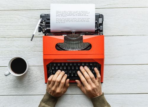 hands typing on red typewriter