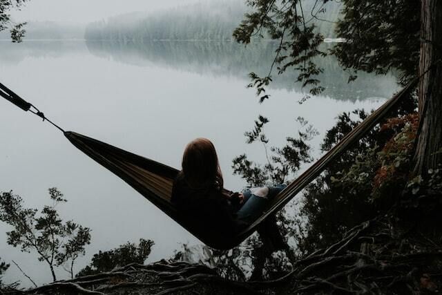 Woman lying in a hammock overlooking a lake