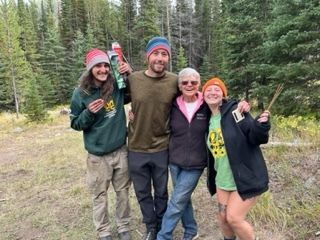 A crew stands smiling with an older woman, Linda the Grandma.