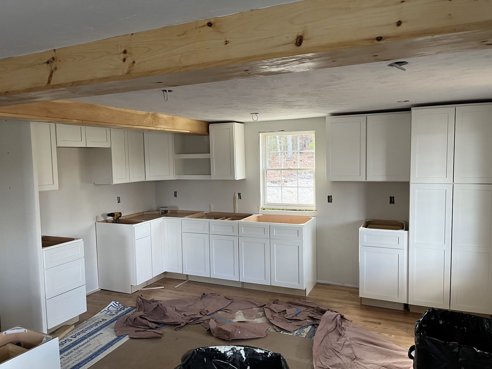A photo showing a kitchen with new white cabinets being installed