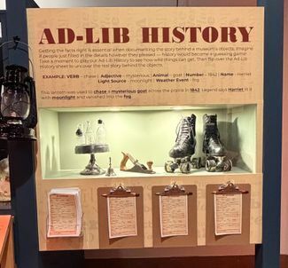 Exhibit display title Ad-Lib History. Three artifacts are in a case with clipboards hung below with questions.