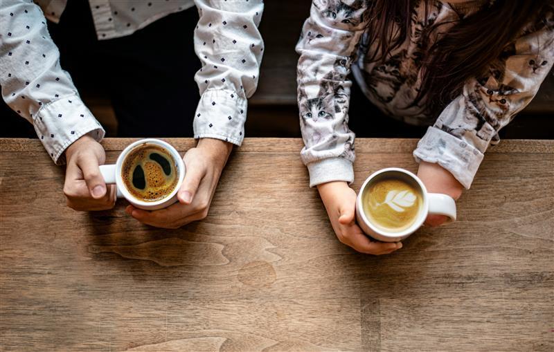 two people holding their own cup of coffee