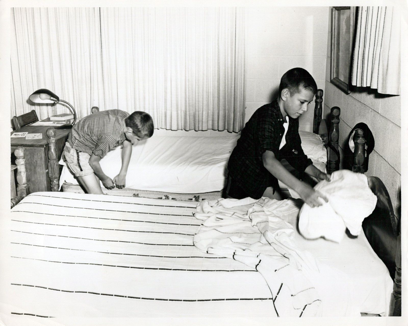 Boys making their beds in their cottage in the 1960s.
