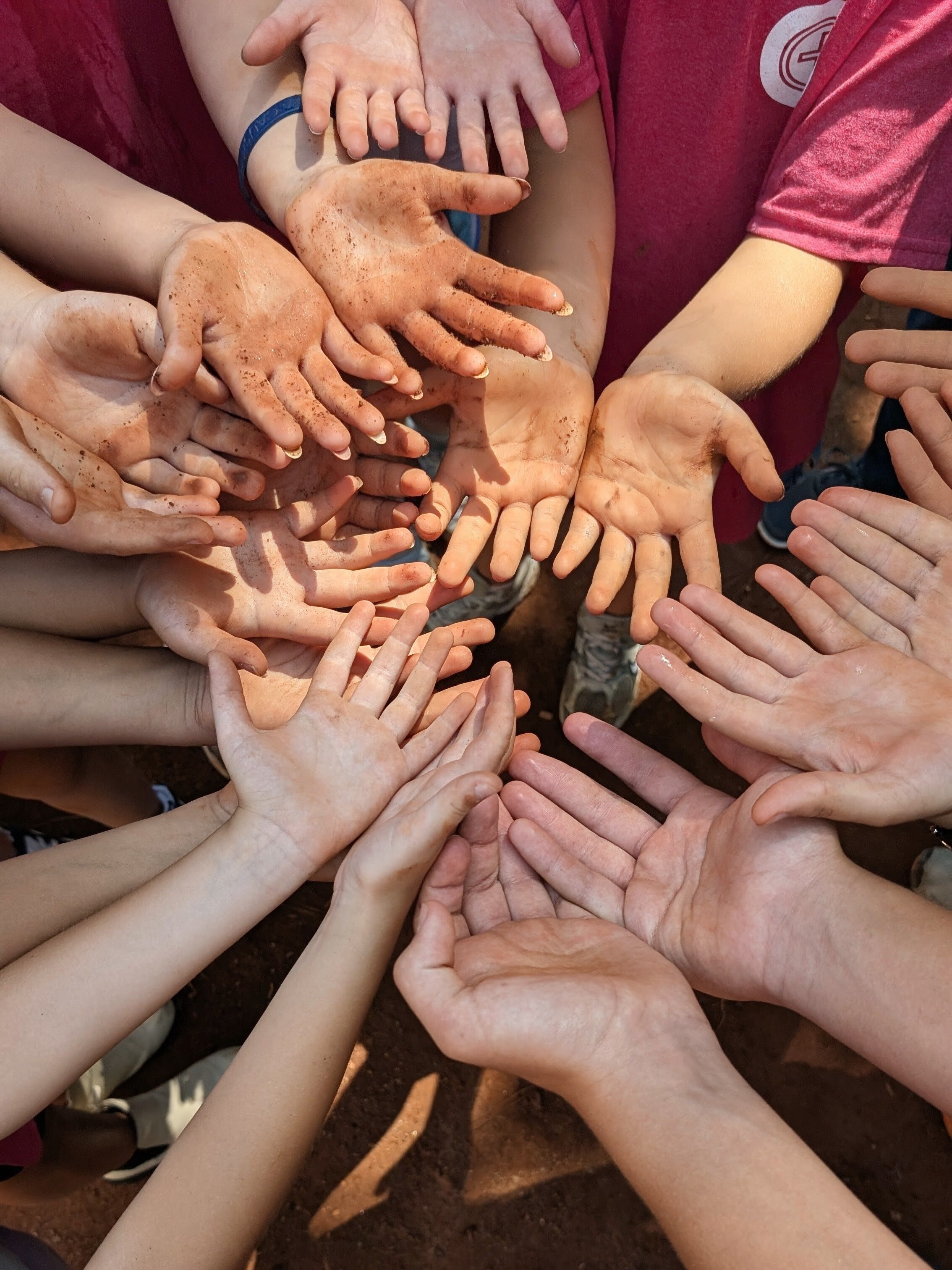 Circle of children's hands reaching toward the center