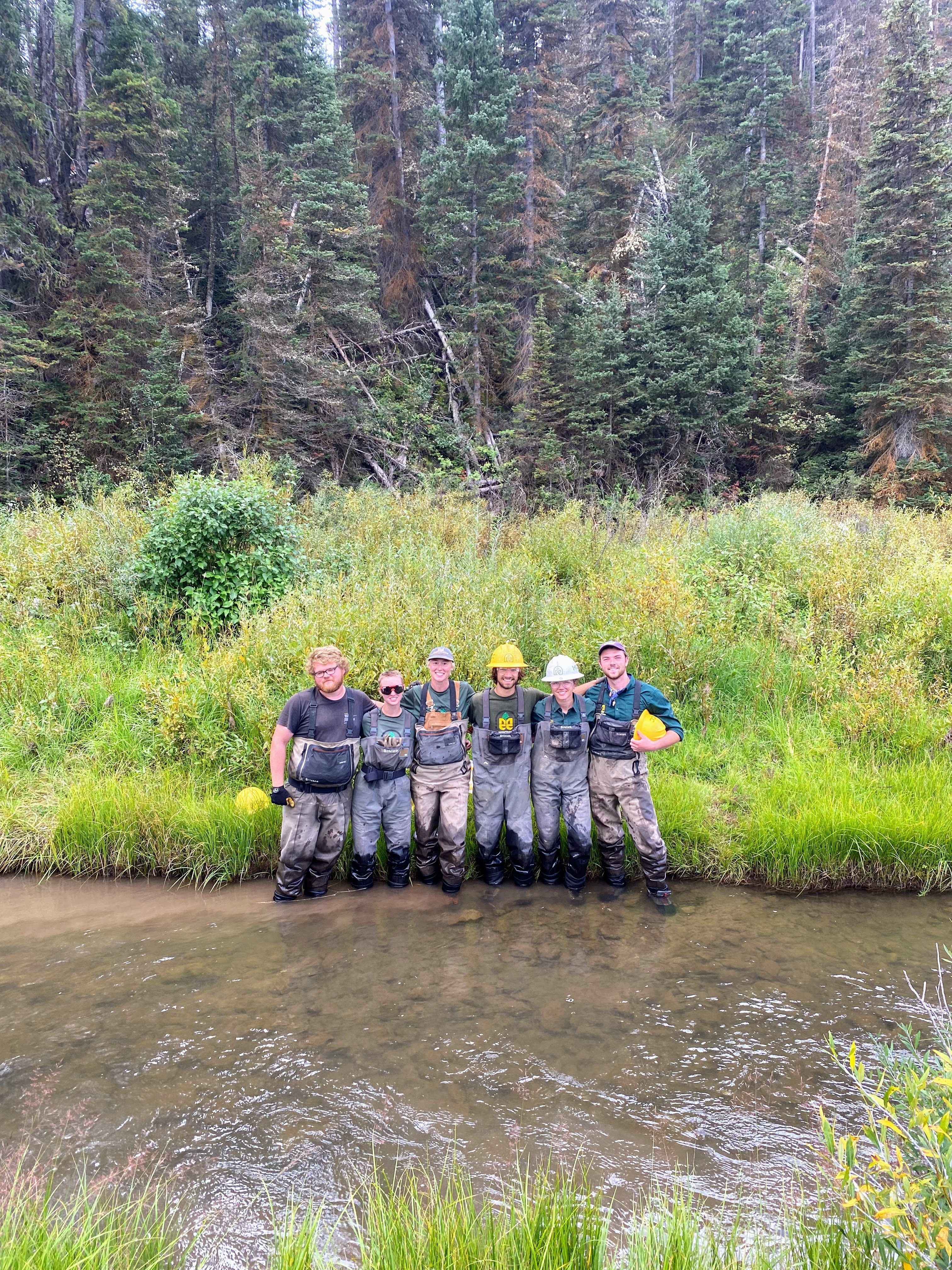 A crew stands in a creek