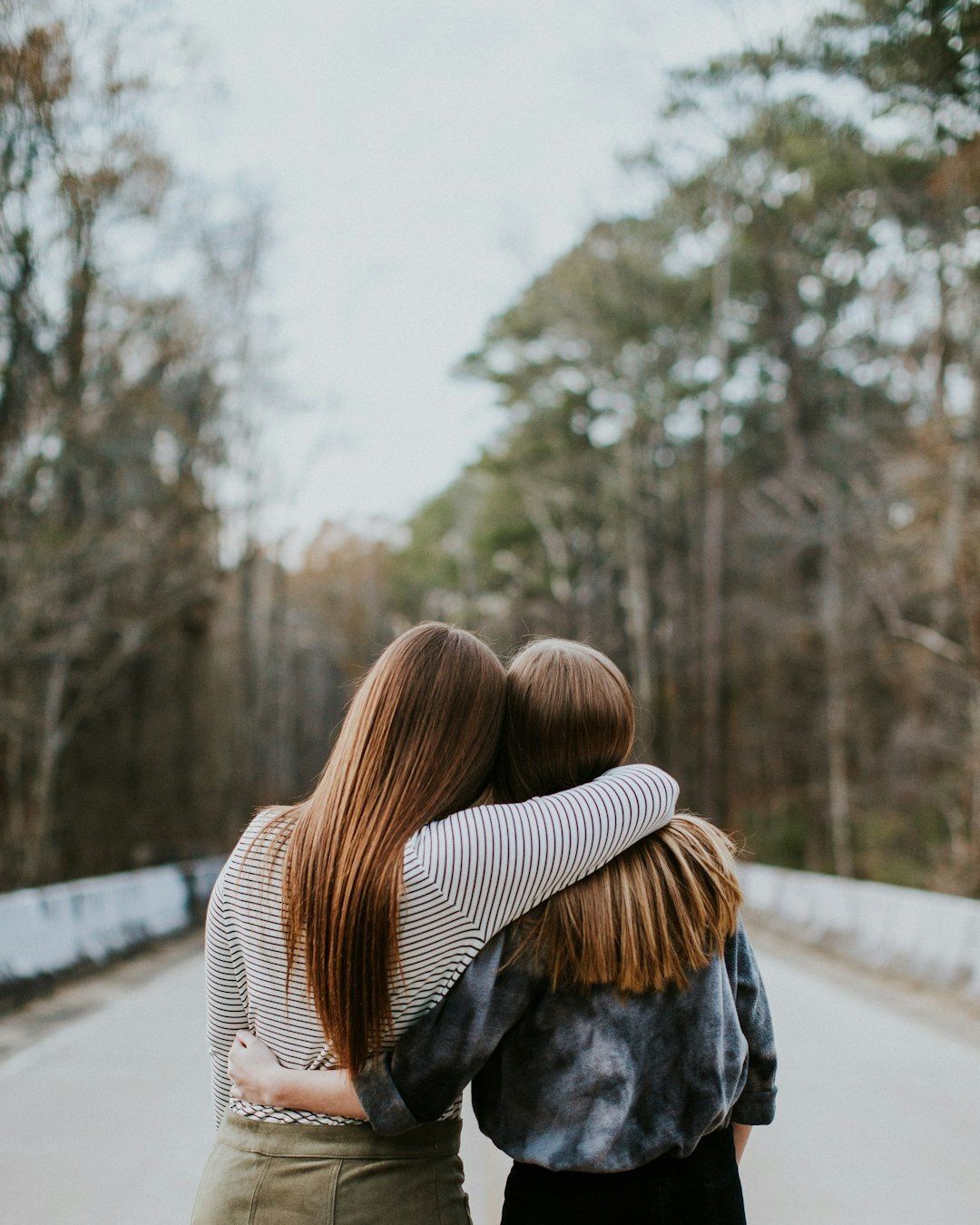 Mother and daughter embracing, as shown from behind