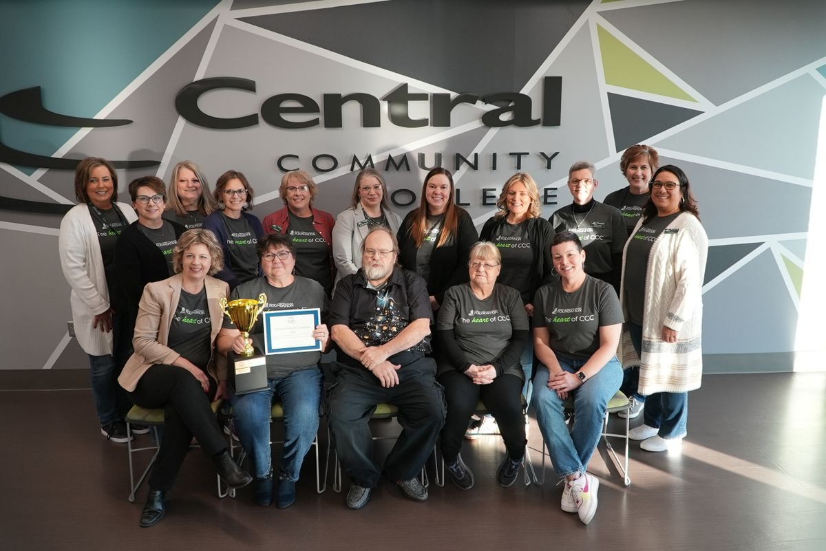 CCC employees all wearing the same shirt with words "the heart of ccc", one row stands behind a row sitting in chairs.