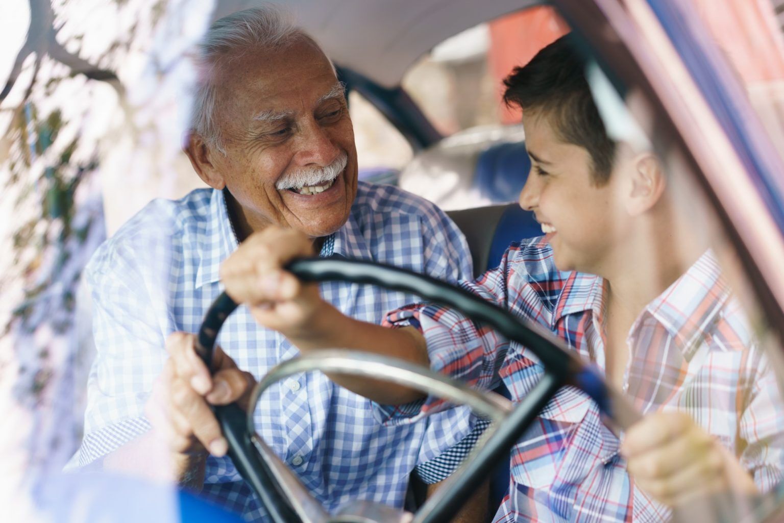 Grandfather smiling at his grandson behind the wheel of his old truck, not driving