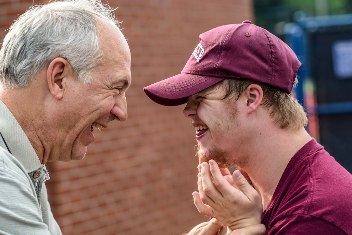 A coach is smiling with a baseball player