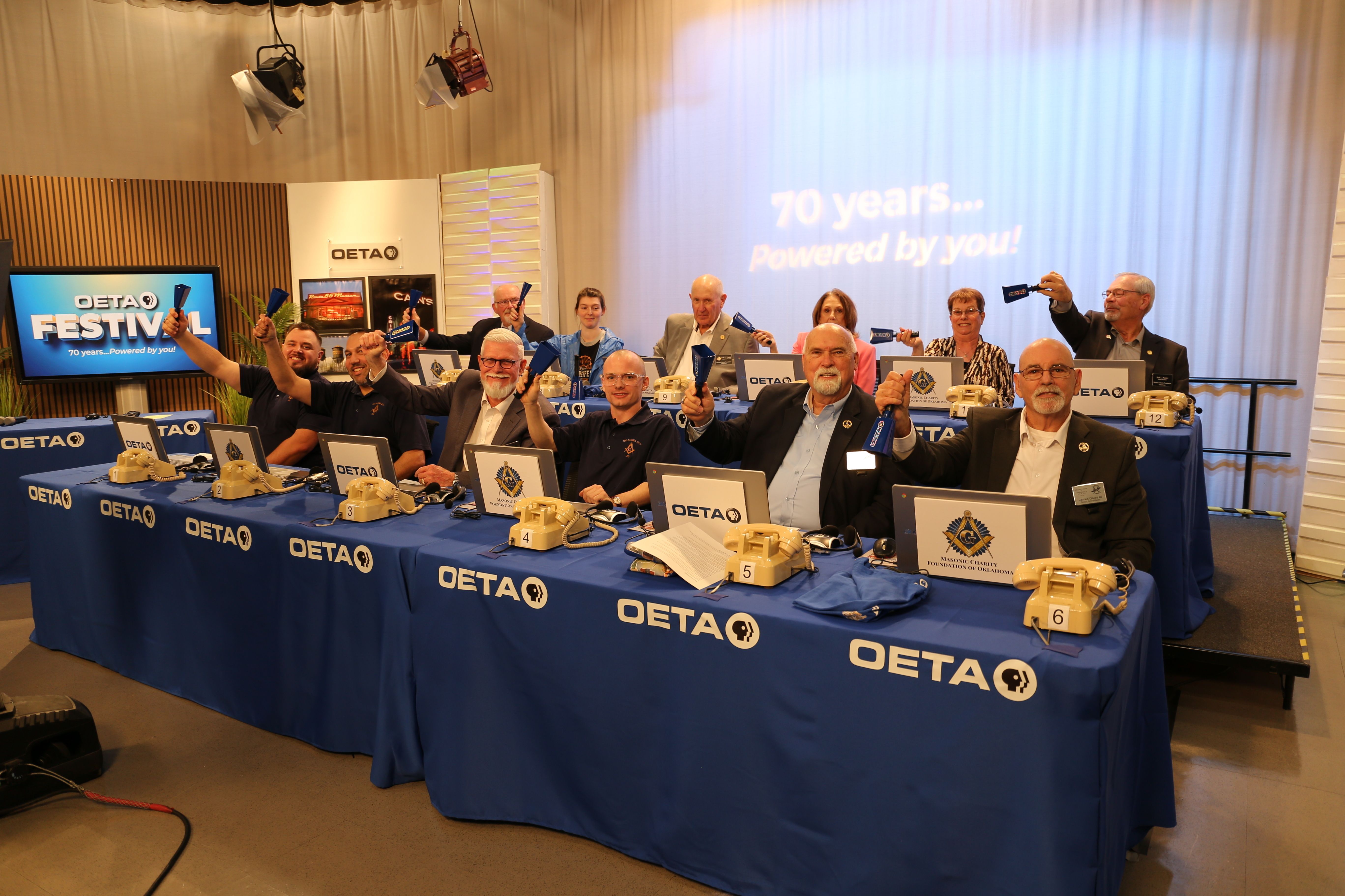 Group of people seated in two rows waving cowbells