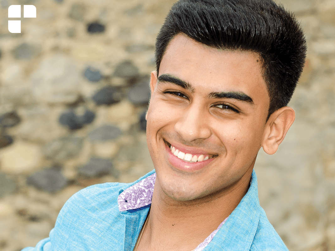 Young middle-eastern man smiling at the camera with a light blue polo on