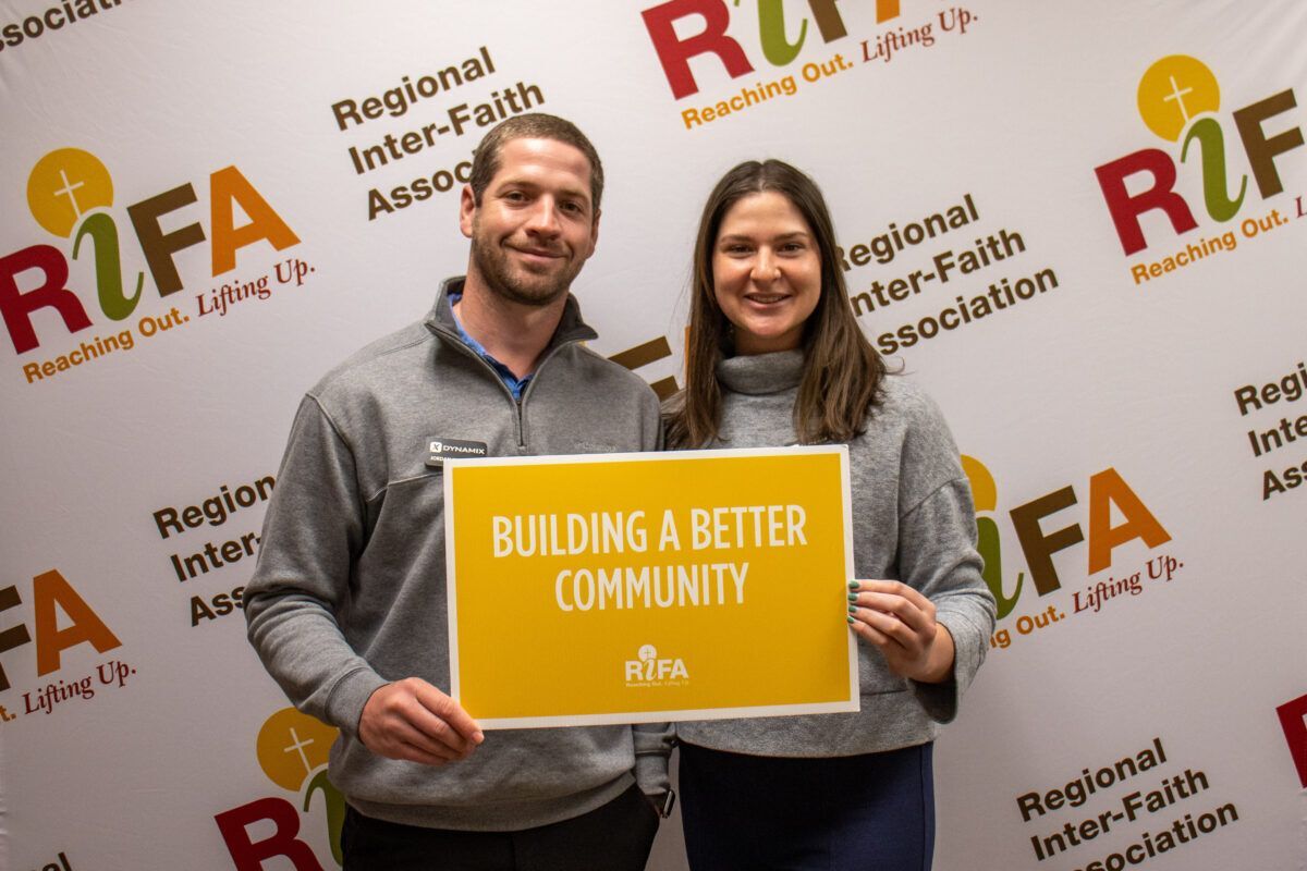 Two people holding a sign reading "Building a Better Community"