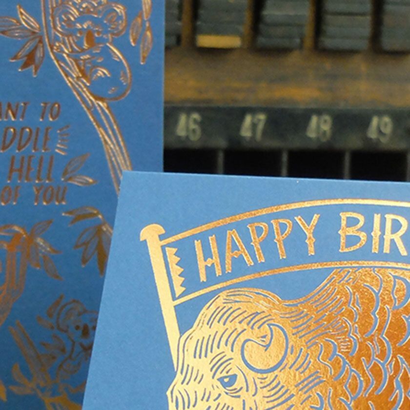 Blue card with gold embossed "HAPPY BIRTHDAY" and bear illustration.
