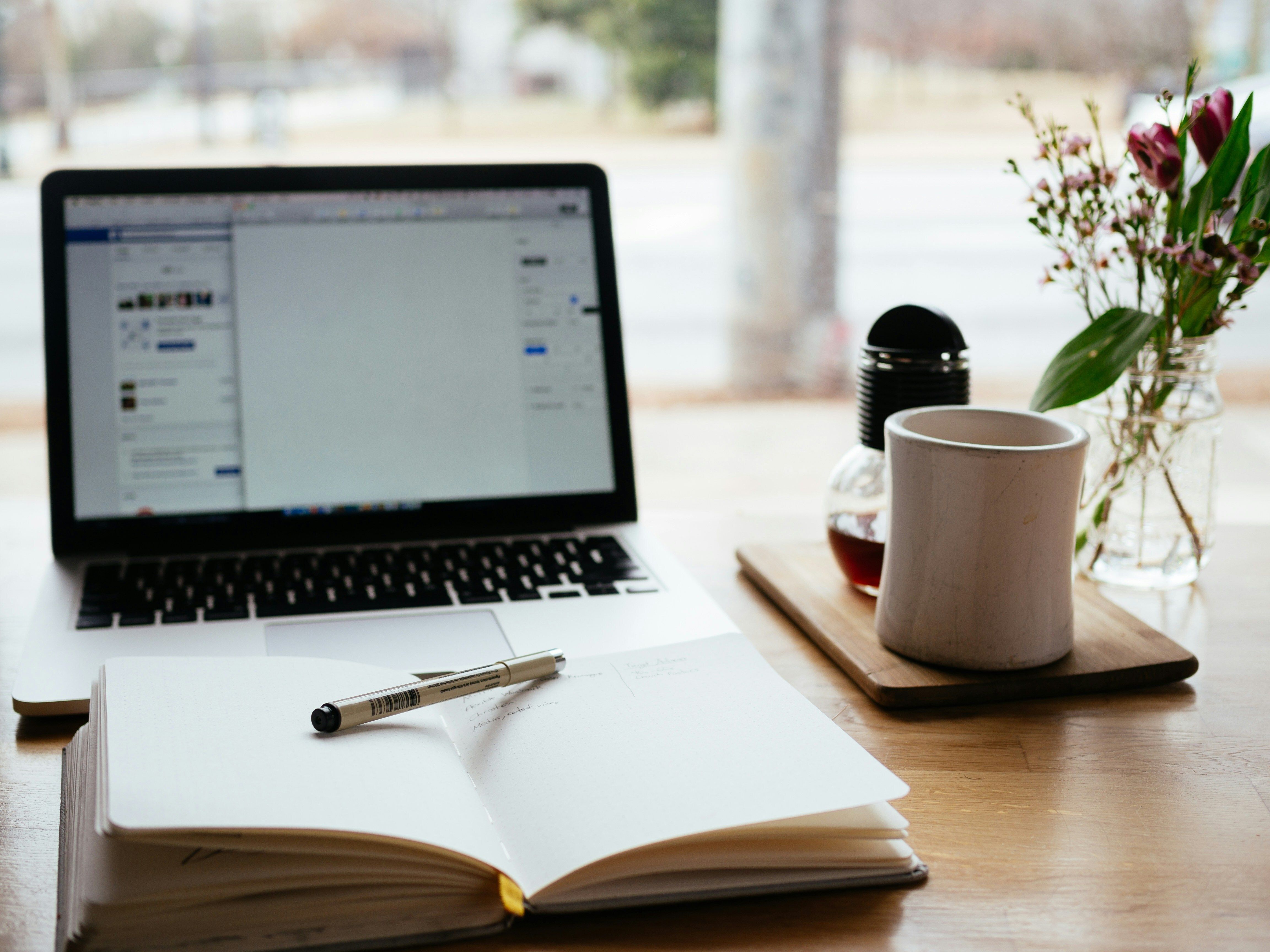 laptop, notebook, and coffee on a desk