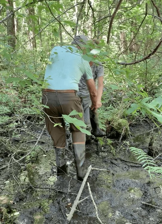 Dale fishing Loti's sister's boots out of the mud