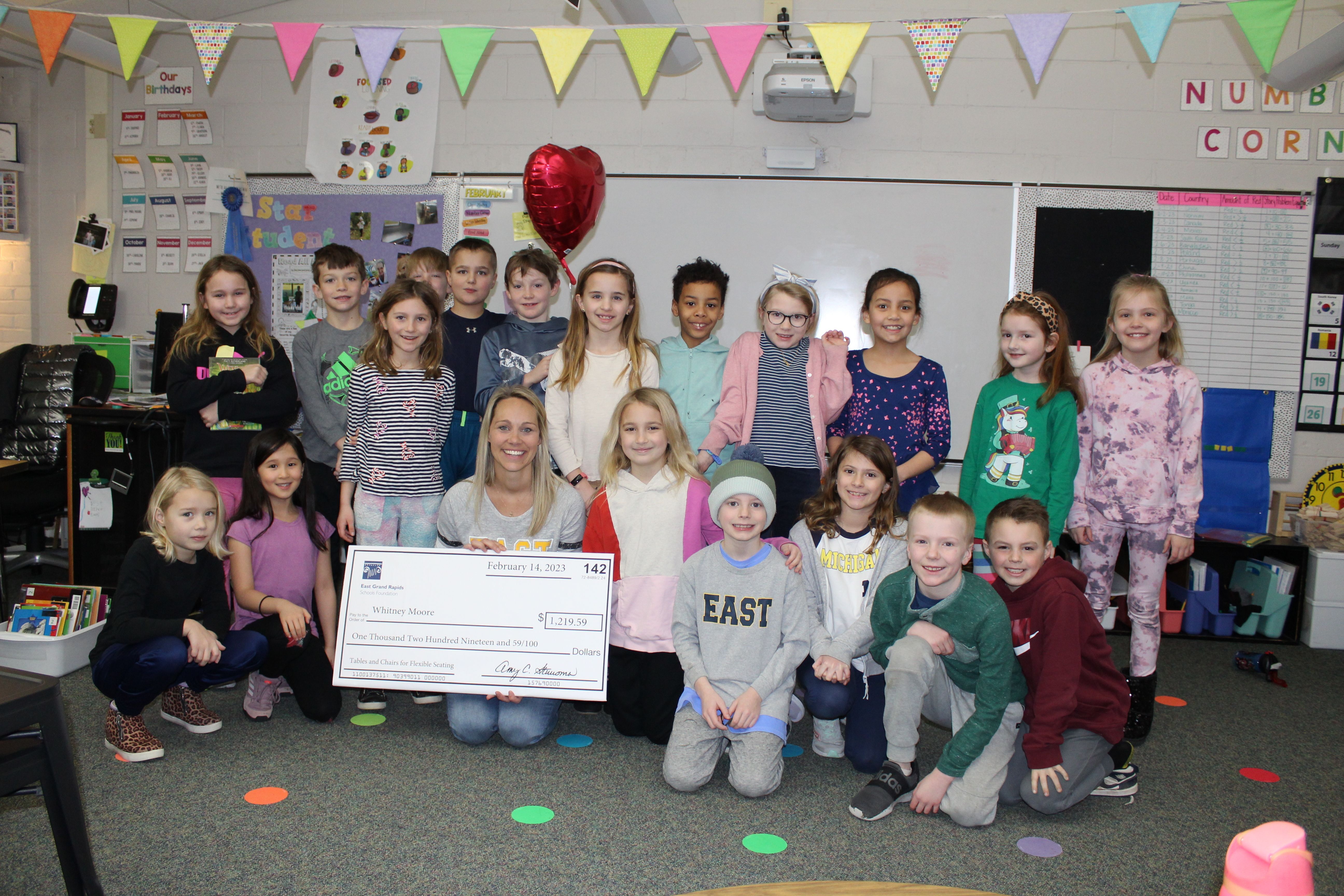 photo of teacher and students with big check
