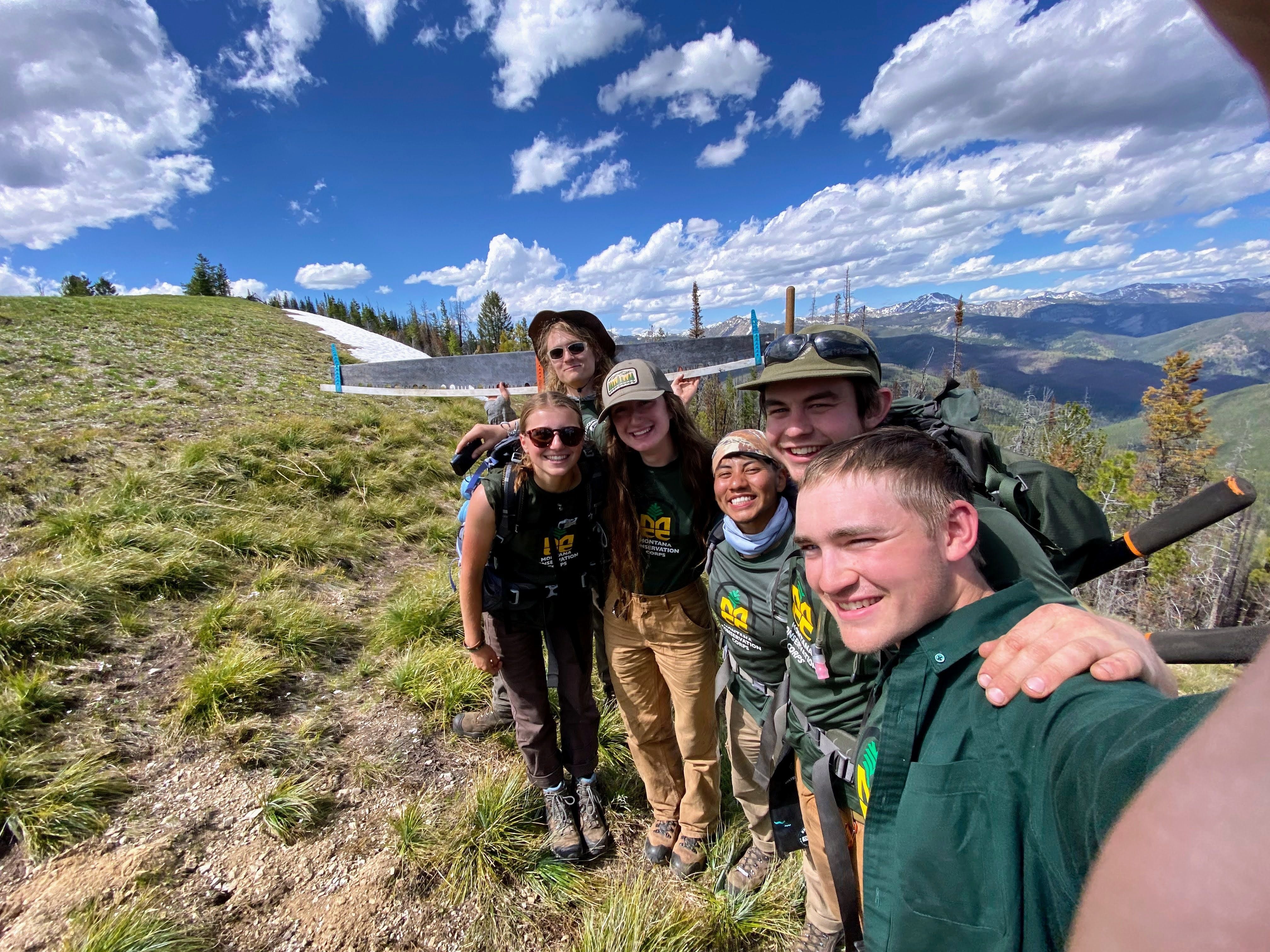 A crew takes a selfie on a hillside