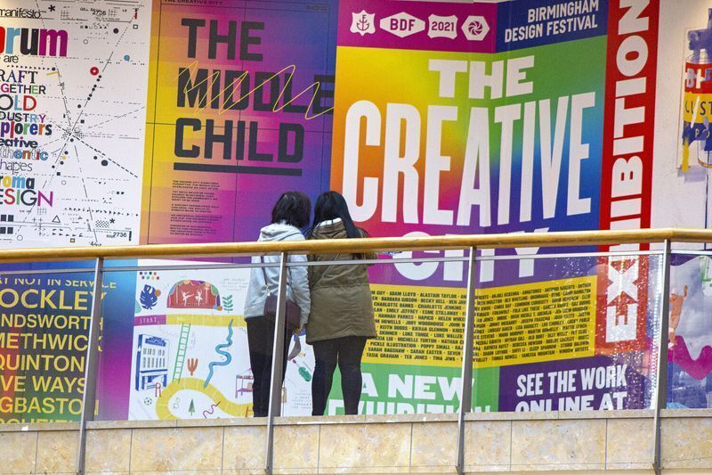 Instagrammable wall ideas from a colorful gallery exhibition display, "The Creative City," viewed by two visitors at Birmingham Design Festival.