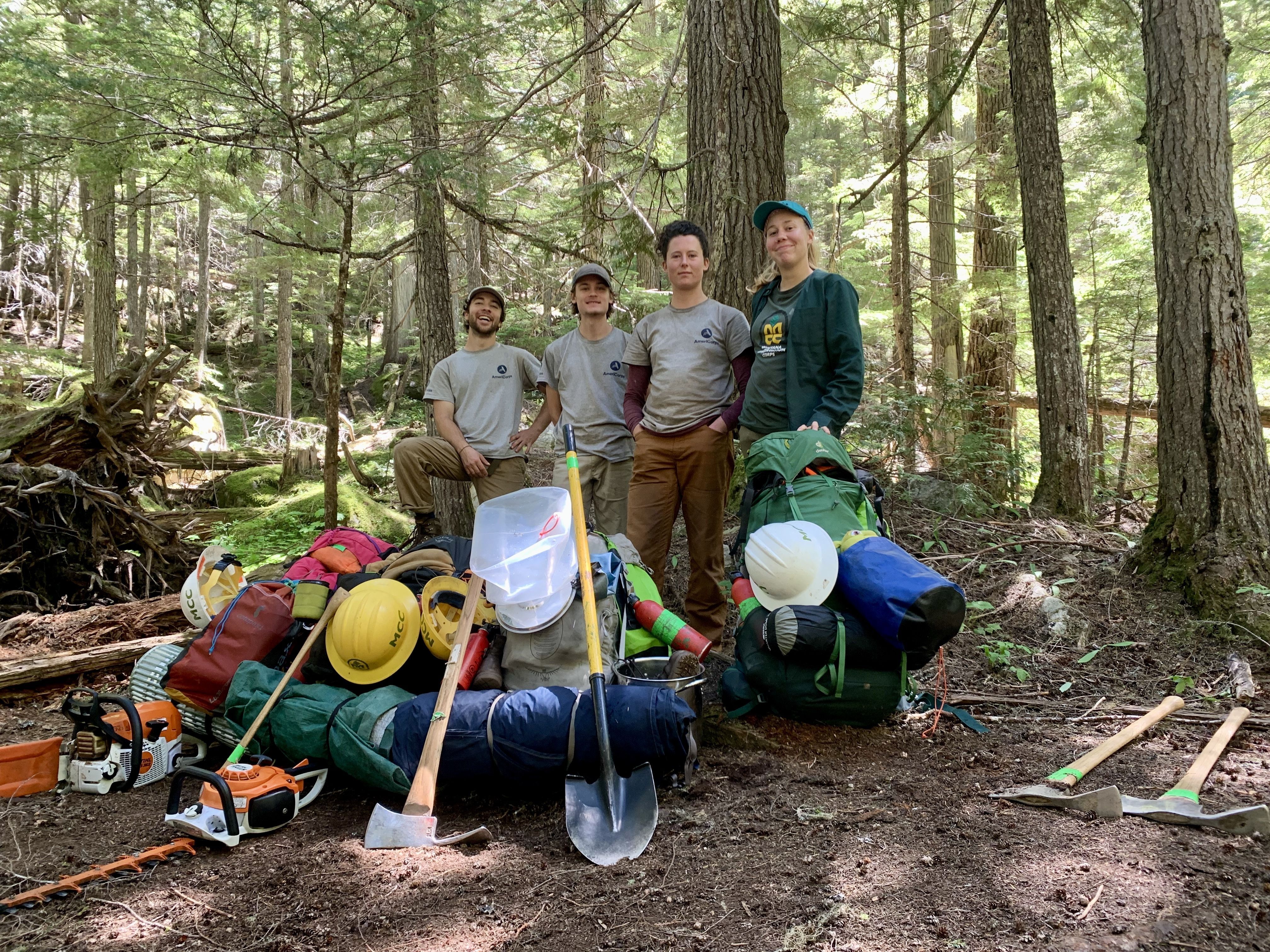 A crew stands smiling behind a massive pile of gear that they had to backpack in!