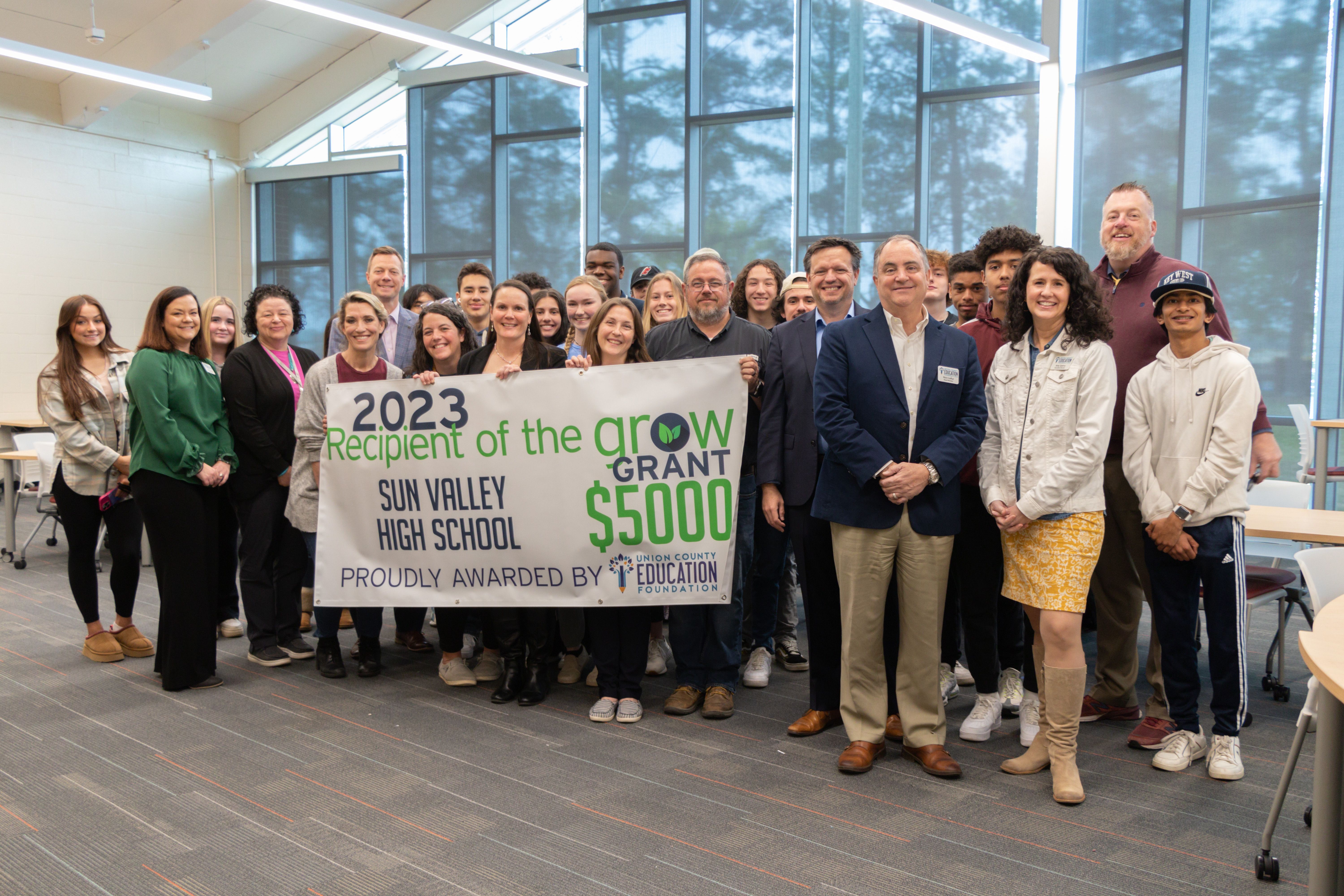 Group of men and women holding a big check.