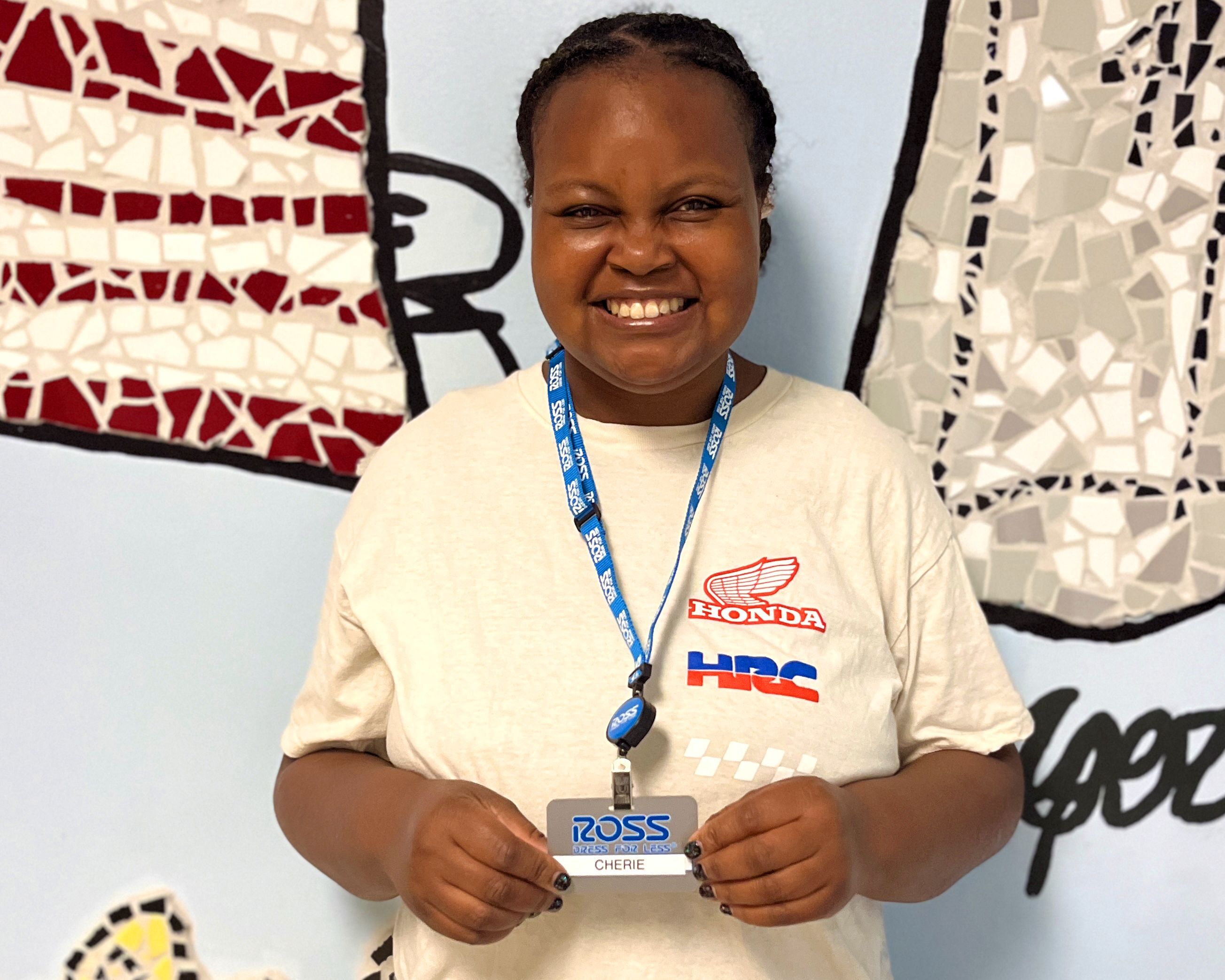 A woman photographed, posing with her ID card from her new job at Ross