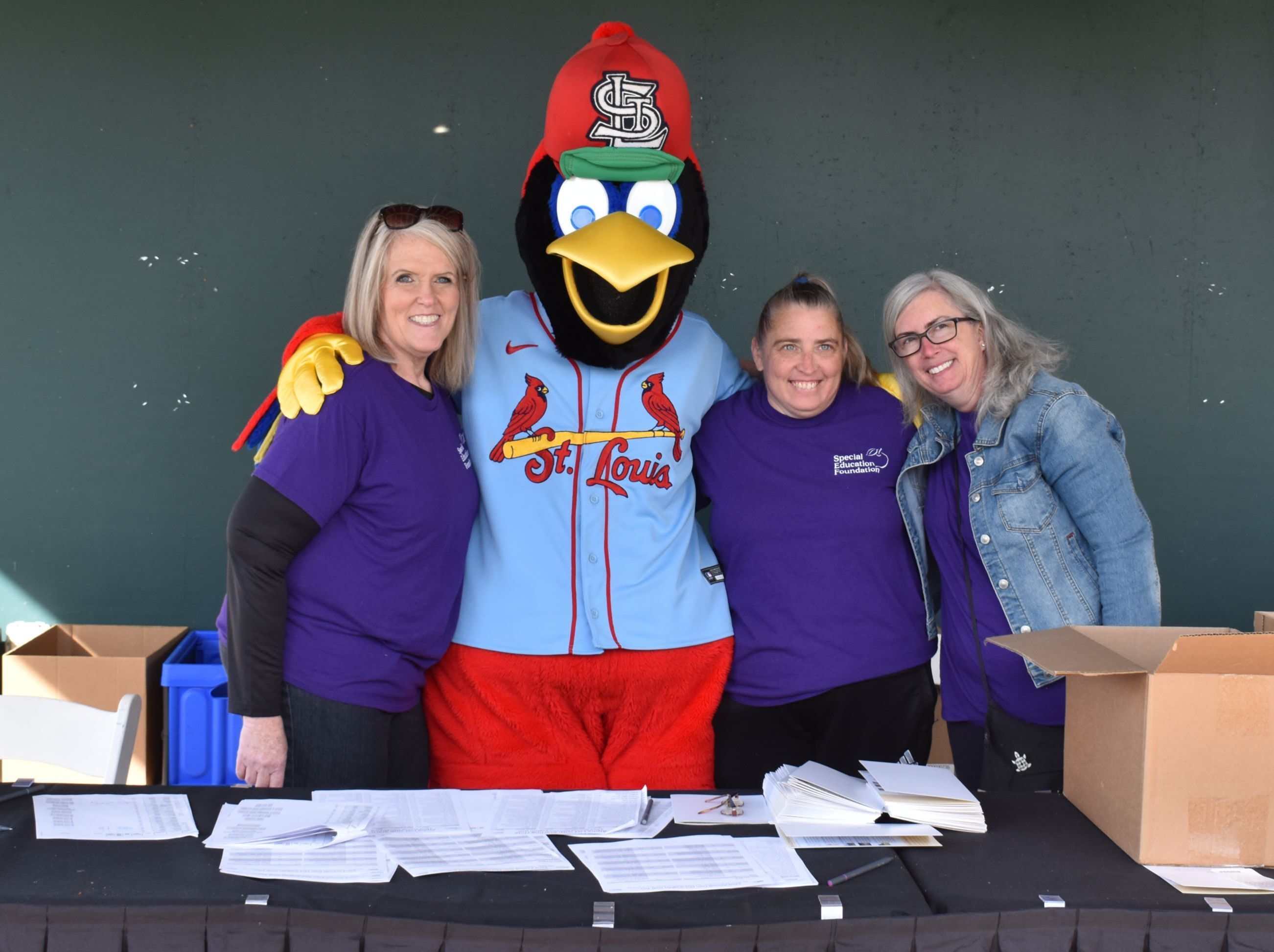 3 women standing with a bird mascot