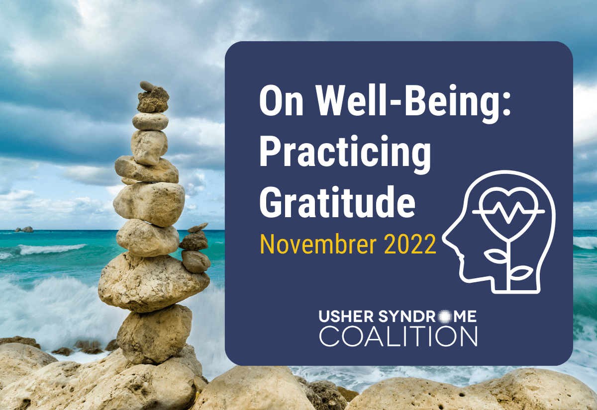A photo of a stack of rocks balanced on the beach with the ocean visible in the background. White and gold text on a navy background reads: On Well-Being: Practicing Gratitude. November 2022. The Usher Syndrome Coalition logo is below the text.