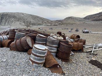 rusted metal barrels partly buried in gravel