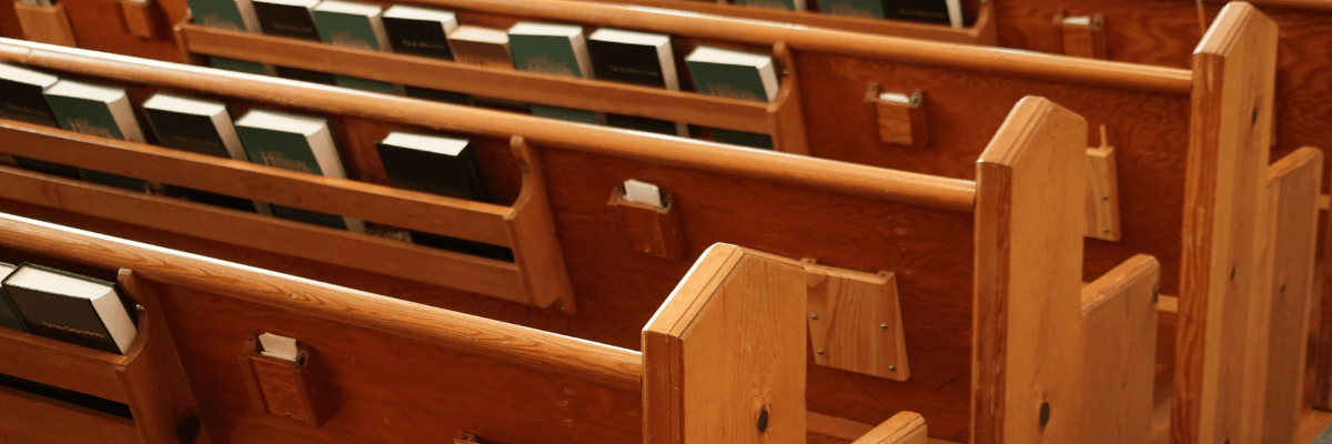 light brown wood pews with bibles and hymnals on the backs of pews