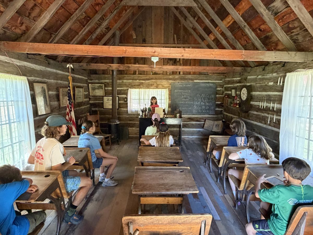 A student speaking in front of other campers inside a historic school house at the Cashmere Museum.