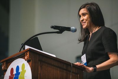 Photo of a female, smiling PSC researcher speaking at a podium.