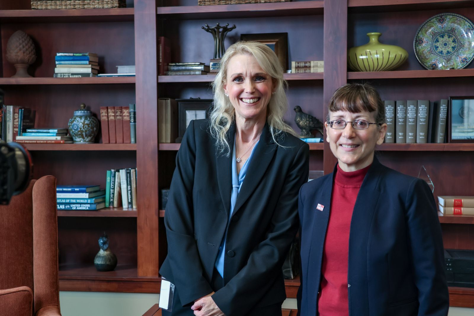 Two women stand in front of a large bookcase
