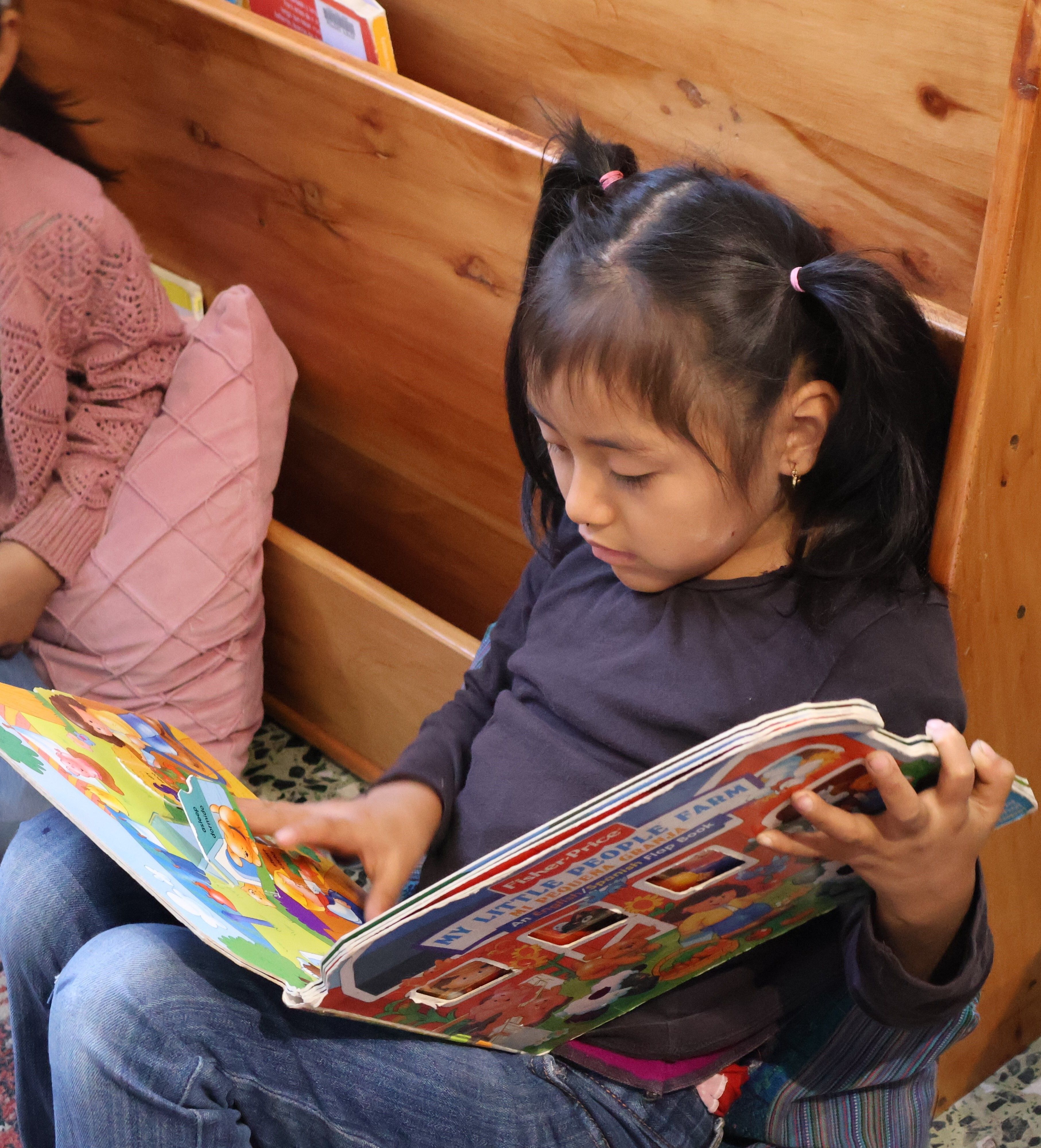 Young girl laying on the ground reading a book.