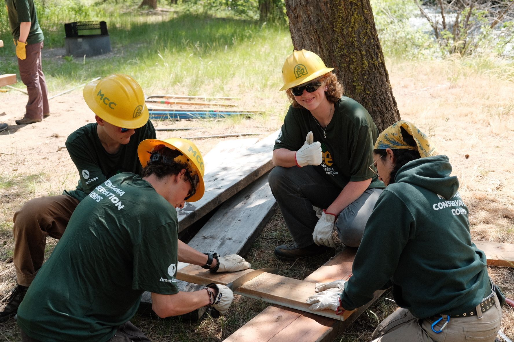 A crew member gives a thumbs up while working with their team on a building project.