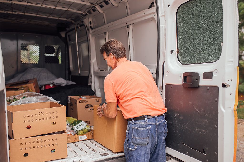 Man loading boxes of food into the back of van.