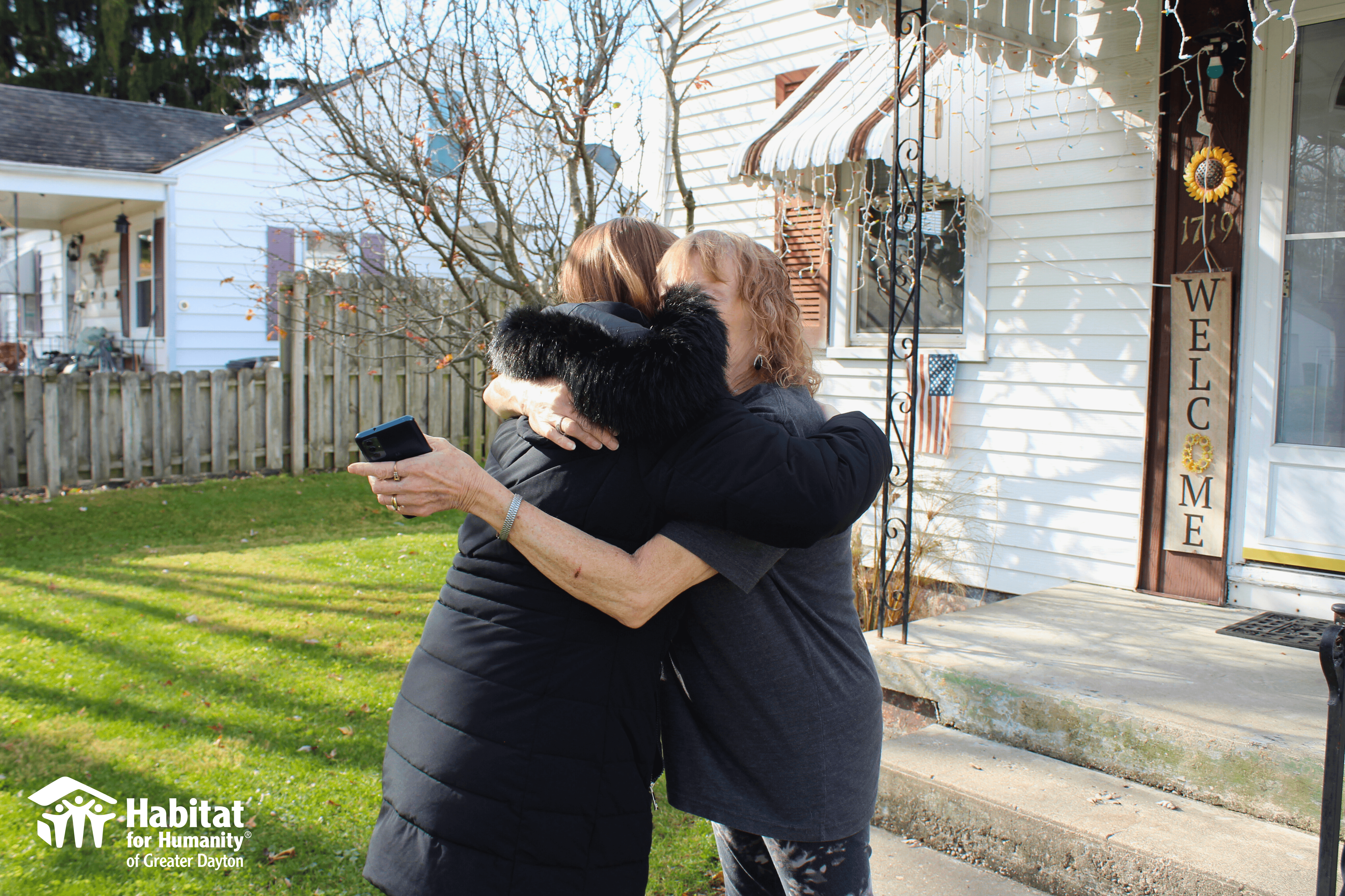 Two women hug outside of a home