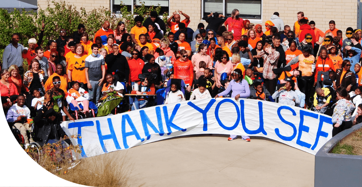 kids outside holding up thank you SEF banner