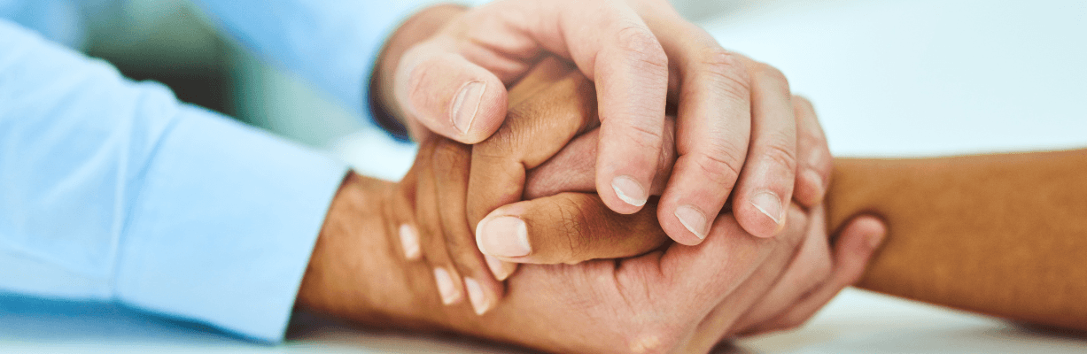 A pair holding hands in a comforting way. 