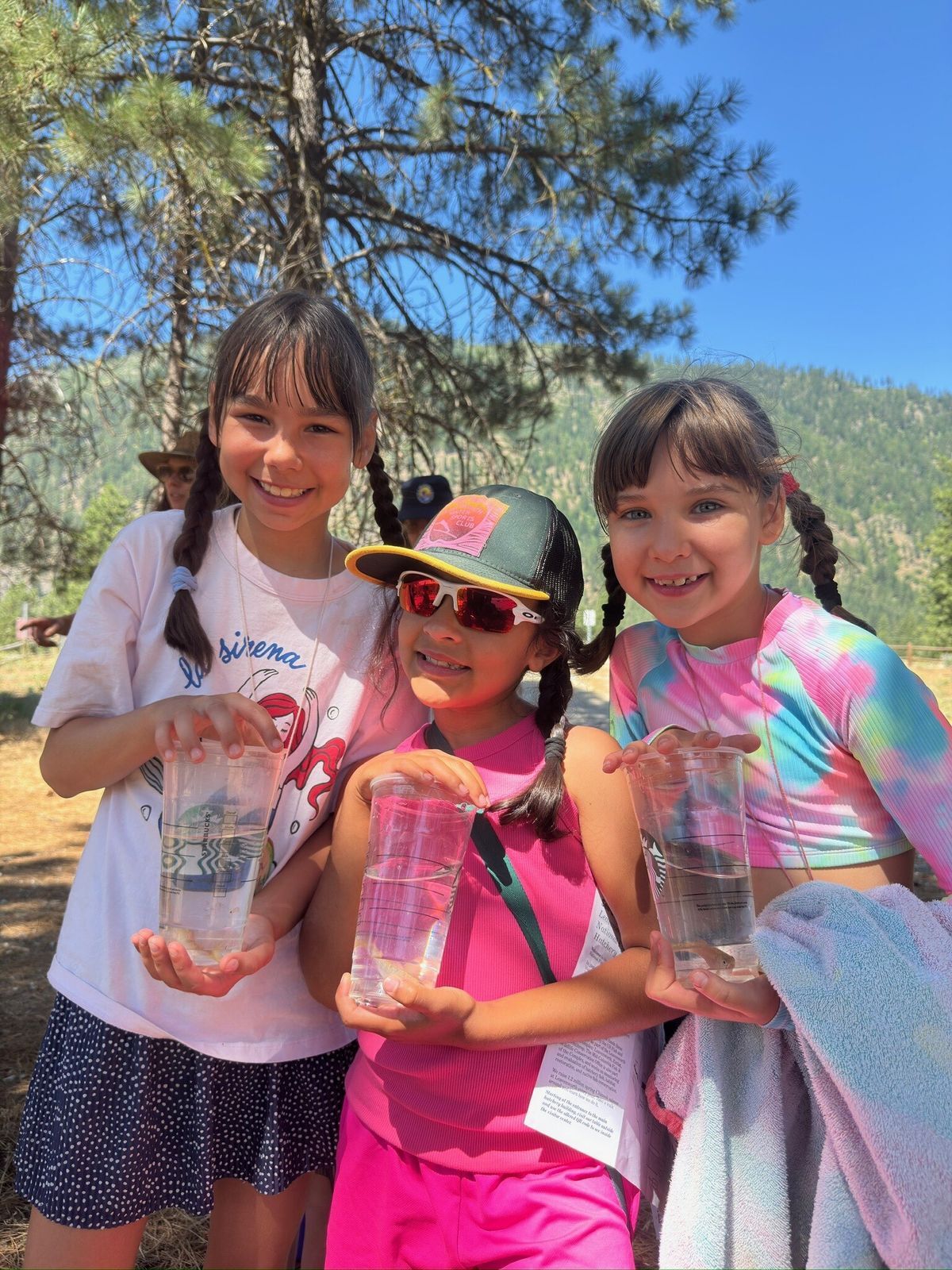 Three young girls pose with their salmon fry that they are about to release into Icicle River during Cool Critters Camp.