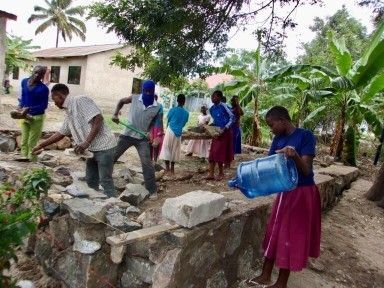 Group of people working on building cement wall.