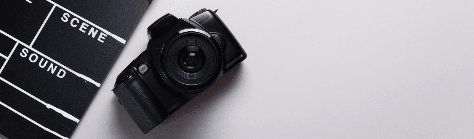Image of a camera and a clapperboard sitting on a table.