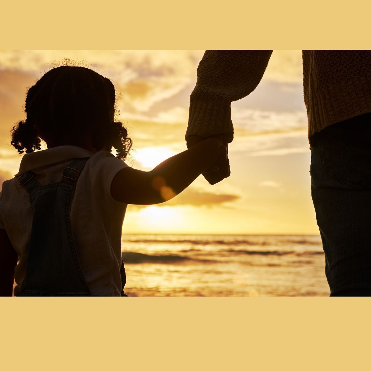 shadow of a child holding parents hand with a beach sunset in the background