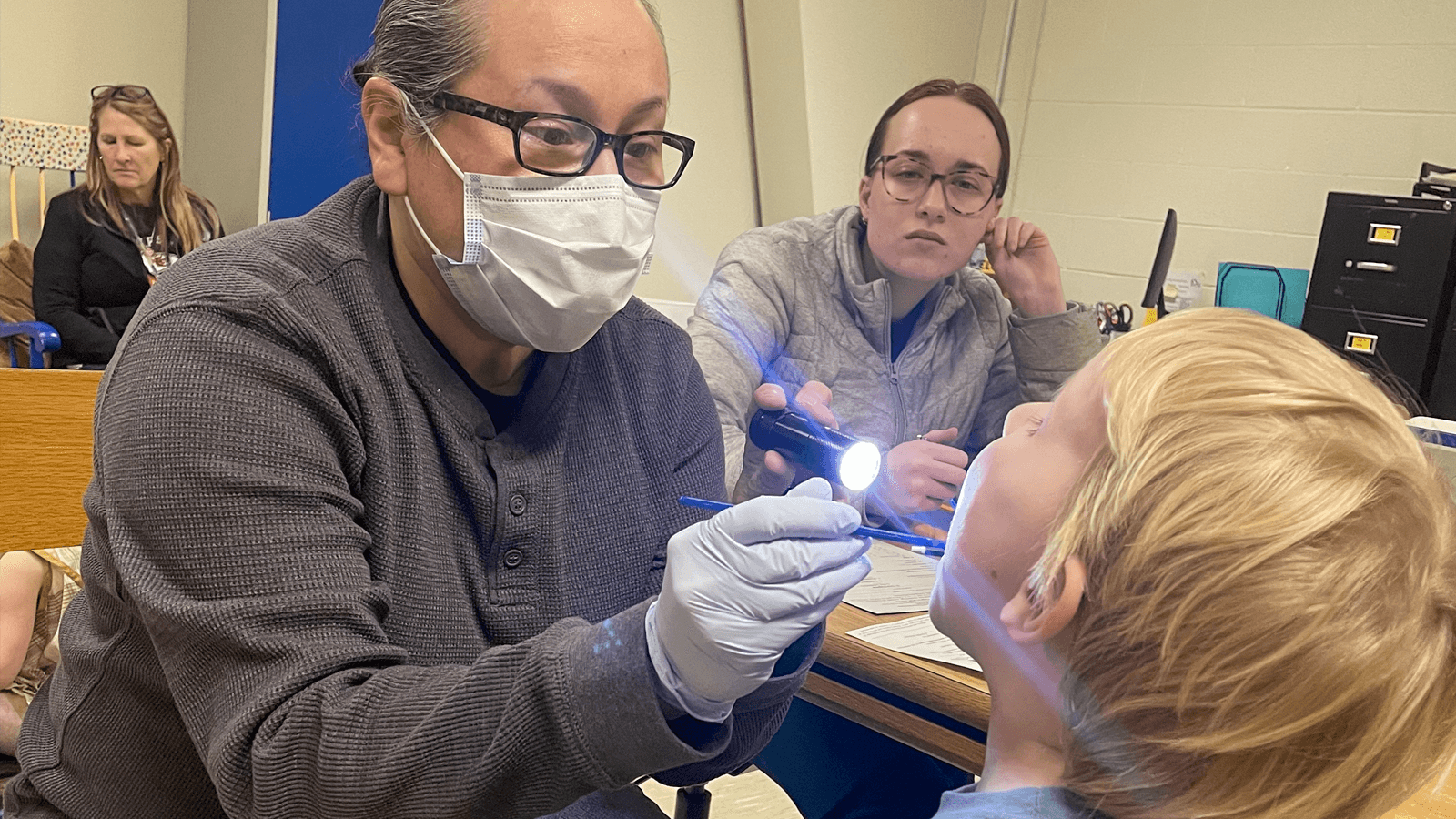 volunteer providing dental screening to young boy