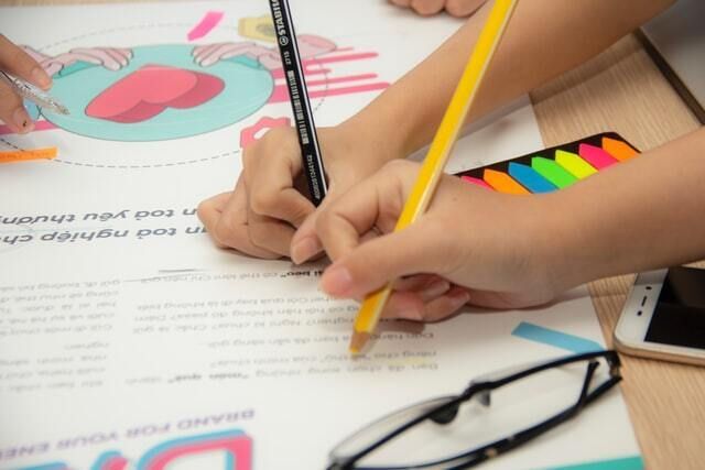 Hands using pencils to write on paper