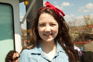 A young girl with PSC and a bright red bow on top of her head stands smiling on a boat ride at a past PSC Partners conference.