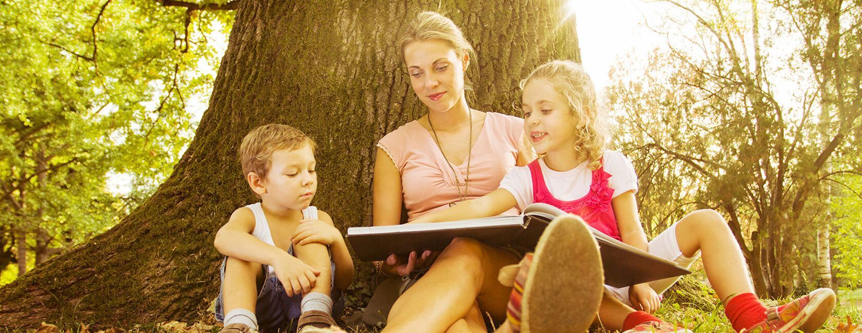 Woman reading book to two young kids