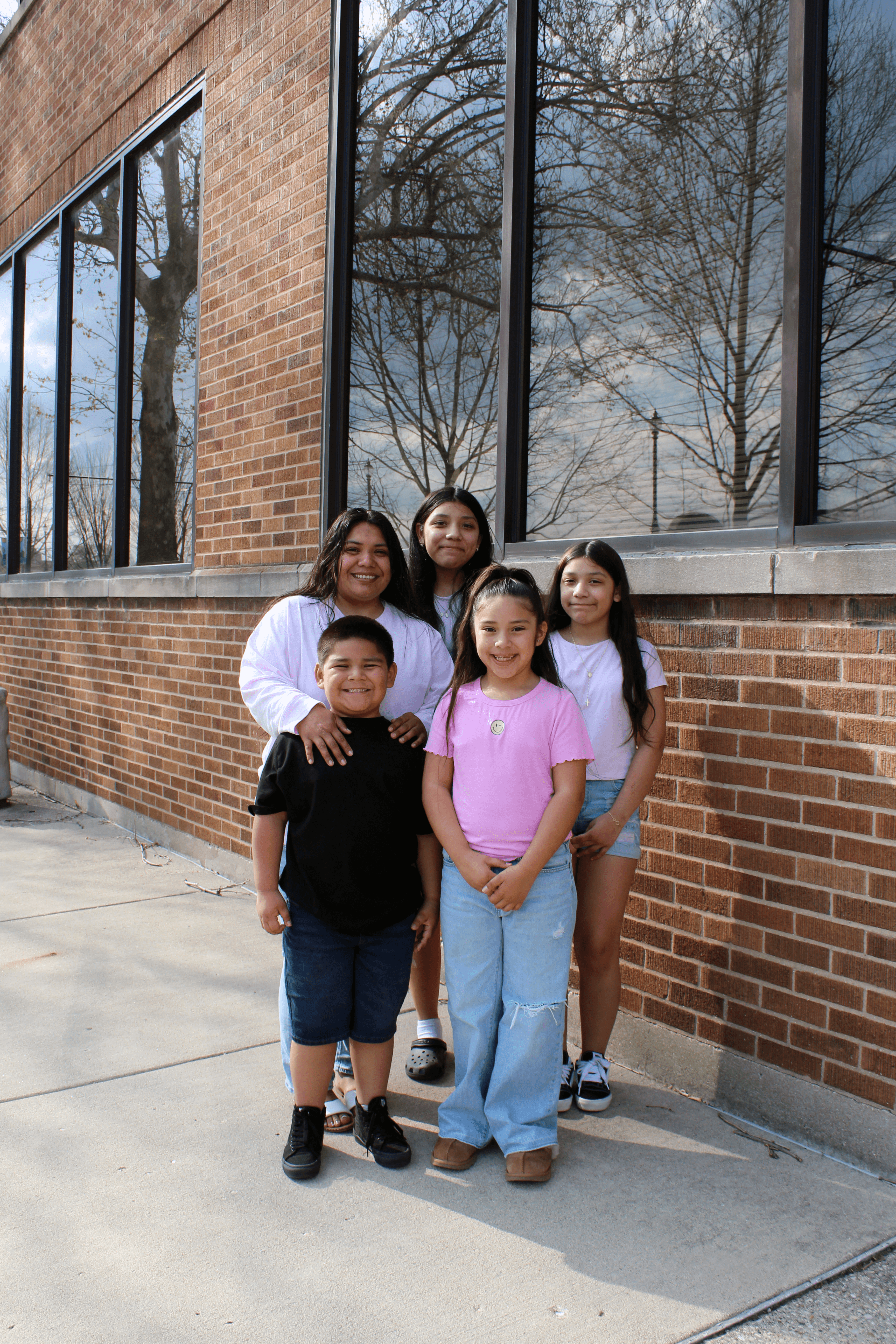 A mother stands with her four children (3 girls and 1 boy)